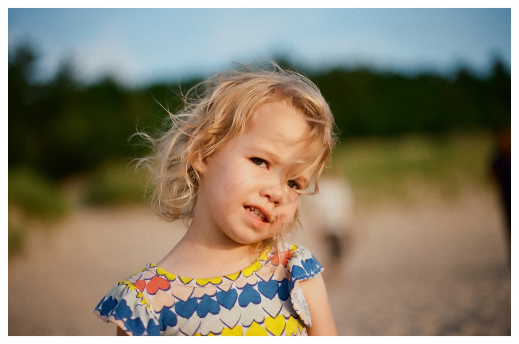 Lily outdoors at golden hour, hair blowing across her face