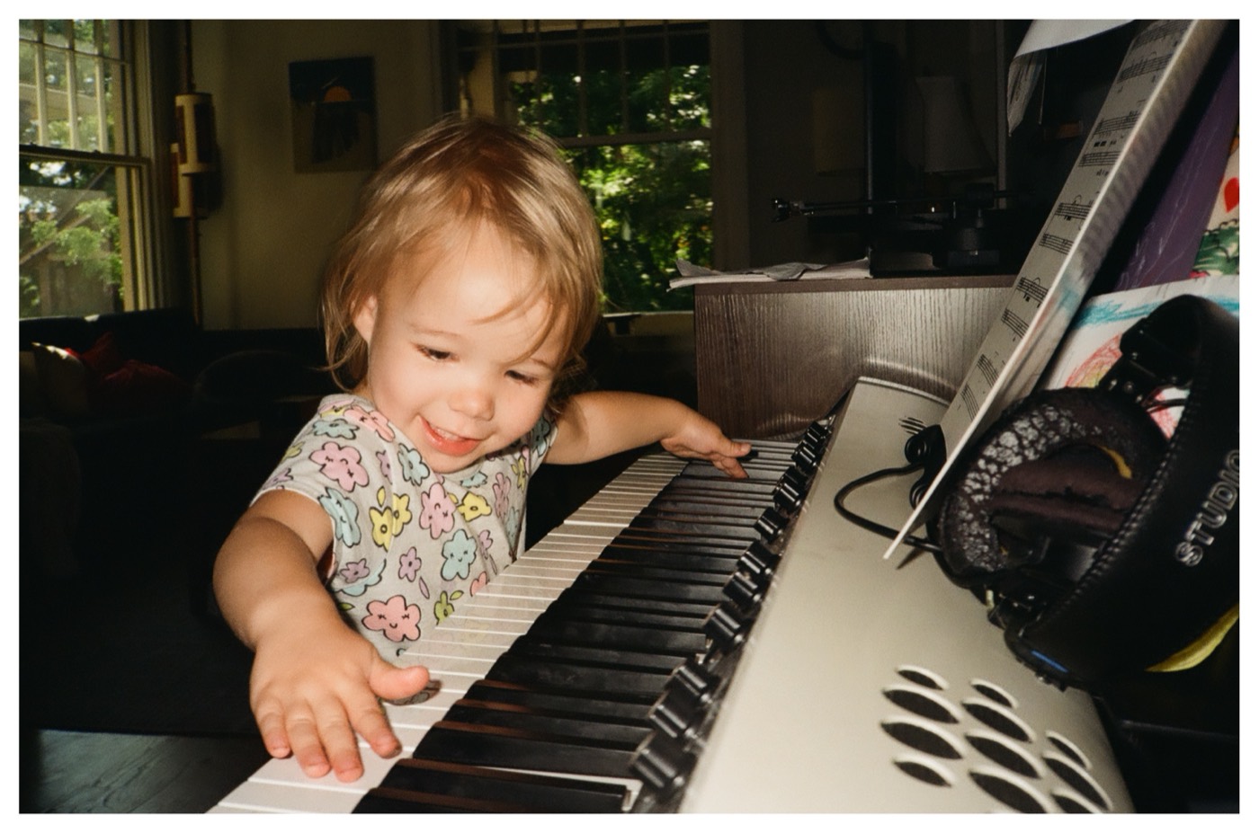 Lily grinning as she plays a keyboard